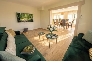 Un salon avec un canapé vert, une table basse et un tableau accroché au mur.