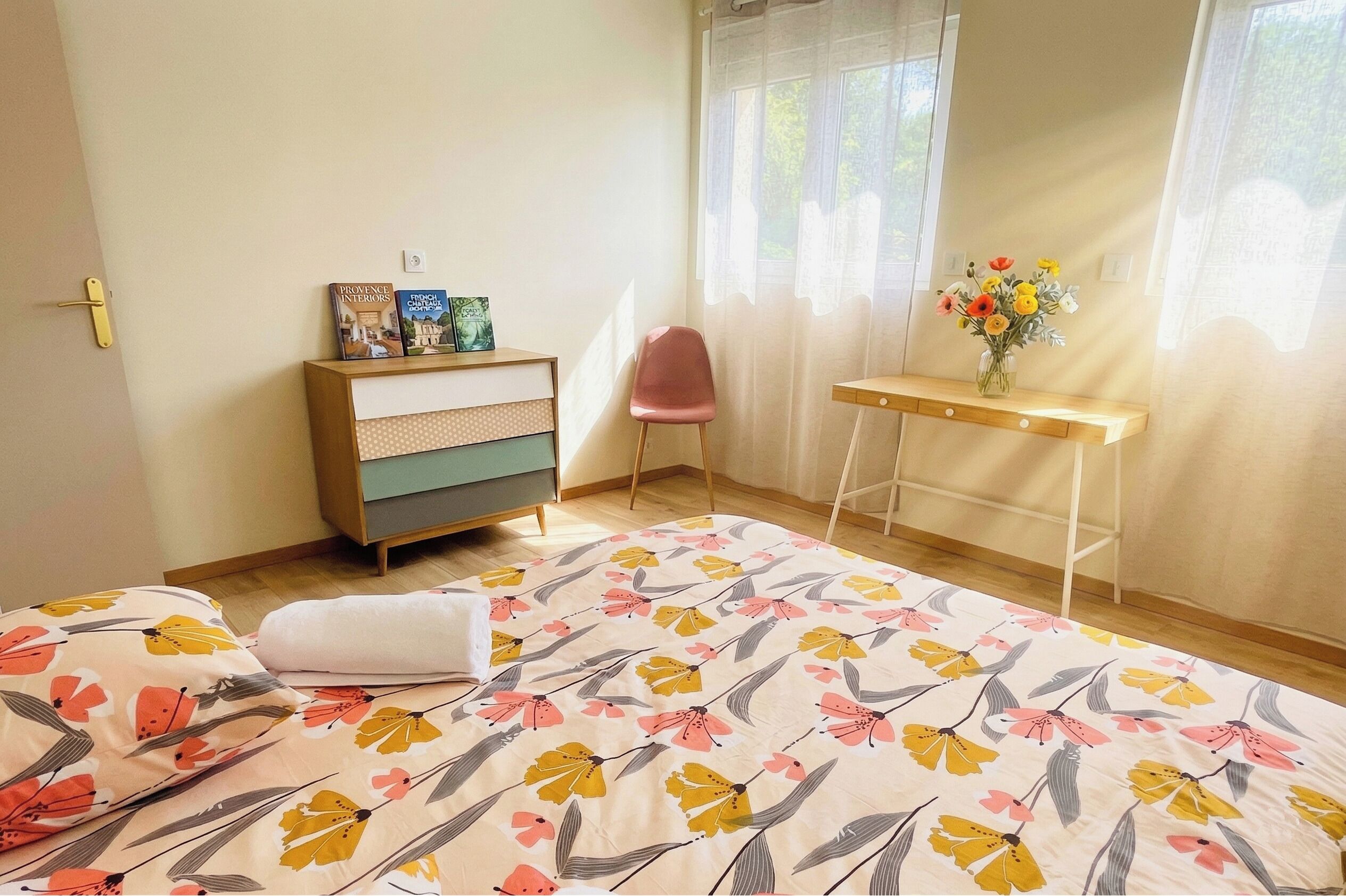 Un dormitorio con cama, cómoda, silla, escritorio y ventana con cortinas.