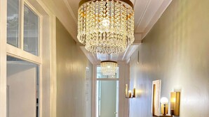 Un couloir doté d’un plancher en bois, d’un lustre et d’appliques murales.