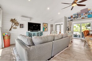 Relax in this stylish living room with a large sofa, flat-screen TV, and ceiling fan.