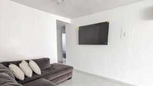 Ein modernes Wohnzimmer mit einer großen Eckcouch, einem flachbildfernseher an der Wand und einem klaren, minimalistischen Design.