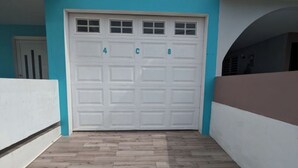 Eine Garage mit weißer Tür, nummerierten Stellplätzen und Holzboden.