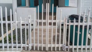 Ein Gebäude mit einer Veranda, weißen Säulen und einem weißen Zaun.