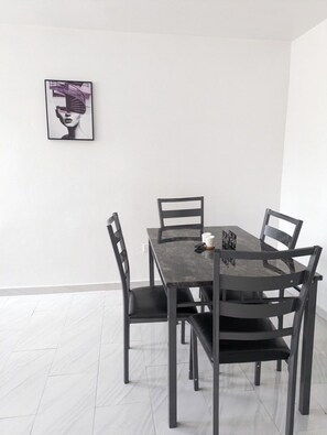 Un coin repas avec une table rectangulaire et quatre chaises. Un tableau encadré est accroché au mur, au-dessus de la table.