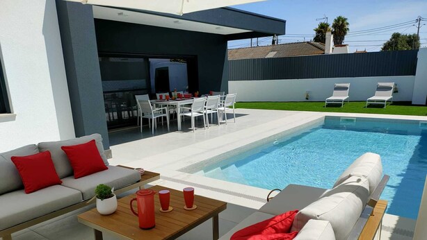 A modern outdoor pool area with a sofa, chairs, and a dining table. - Fantastic holiday home with heated pool (azeitão)