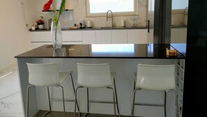 A modern kitchen with a marble backsplash, a large window, and a central island with bar stools. - Fantastic holiday home with heated pool (azeitão)