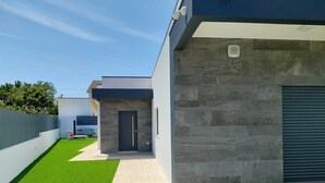 A modern house with a paved driveway, a small front yard with artificial grass, and a garage with a closed roller door. - Fantastic holiday home with heated pool (azeitão)