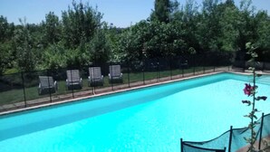 Piscina amb aigua transparent de color blau, envoltada per una tanca i arbres.