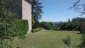 Edifici de pedra amb un jardí ben cuidat i vistes al camp.