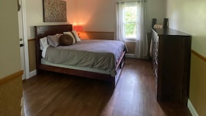 A bedroom with a wooden bed, a dresser, a ceiling light, and a window with curtains. - Whitley Woods Cottage, secluded on 80 acres, Chadwick MO (Chadwick)