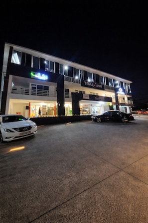 Un edificio de varios pisos con un cartel que dice 'TRAINING', un coche estacionado adelante y una pasarela para peatones.
