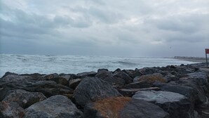 Un rivage rocheux où les vagues s’écrasent contre les rochers sous un ciel nuageux.