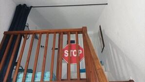 Un escalier en bois avec un panneau de signalisation indiquant un arrêt, suspendu à la rambarde.