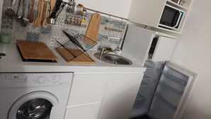Une cuisine compacte équipée d’un lave-linge, d’un four à micro-ondes et d’un évier.