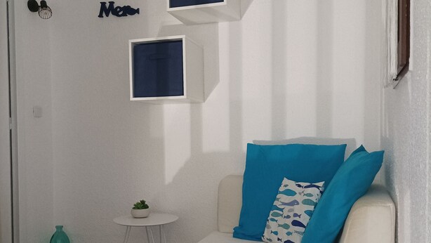 Une chambre à coucher avec un lit, une petite table sur laquelle est posée une plante, et deux armoires fixées au mur.