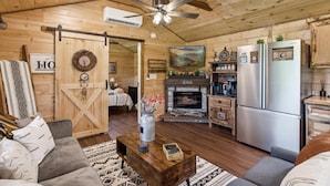 A cozy cabin interior with a living room, kitchen, and fireplace.