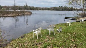 A lakeside view with chairs and a dock.