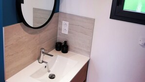 A bathroom with a white sink, wooden cabinet, and a mirror. - Villa Romantique (ANDANCETTE)
