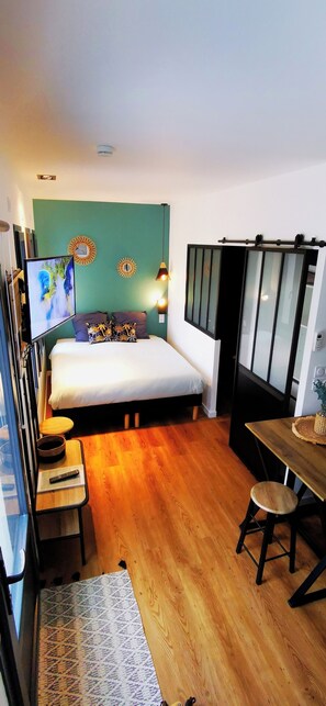 Et lille hotelværelse med seng, et lille bord, en stol og et fjernsyn.