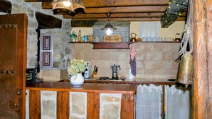 Una cucina rustica con parete in pietra, travi in legno, lampadario a sospensione, mensola con utensili da cucina e un cartello con scritto 