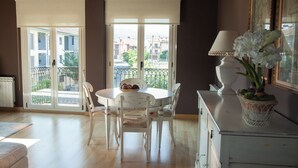 A room with a round dining table, white chairs, a white cabinet, and a potted plant. - Apartamento Sorkun (Lakuntza)