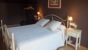 A neatly made bed with a white quilt, two bedside tables with lamps, a framed picture on the wall, and a wardrobe in the background. - Apartamento Sorkun (Lakuntza)