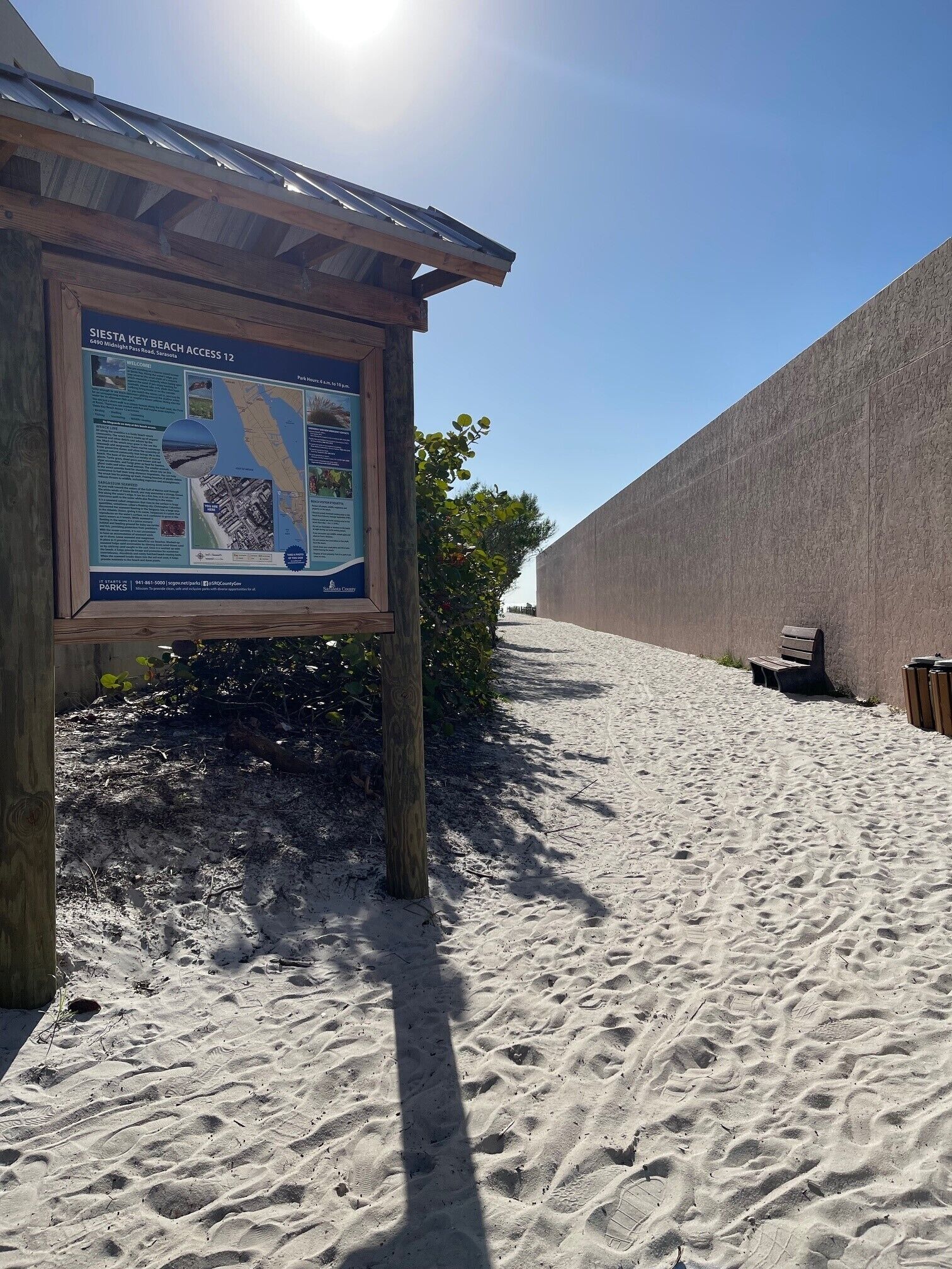 A sandy beach with a wooden signboard displaying information.
