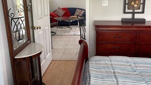 A bedroom with a bed, dresser, mirror, and artwork on the wall. - Walk to Siesta Key Beach. 1 BR condo on ground floor, steps away from the pool (Sarasota)