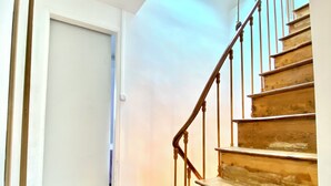 A staircase with wooden steps and metal railings, leading to a room with a white door and a skylight. - Beau Duplex à Deux pas du Port (Le Tréport)