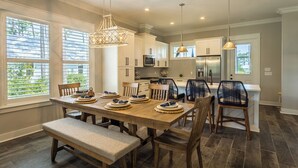 A dining area with a wooden table set for four, surrounded by dark wooden chairs.