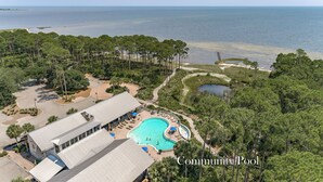 A community pool surrounded by lush greenery and a view of the ocean.