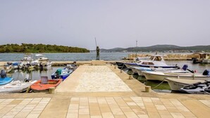 A marina with boats docked, a statue in the center, and a hilly landscape in the background. - Apartment Franka by Interhome (Pašman/Pašman)