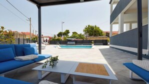 An outdoor patio area with blue sofas, a wooden coffee table, and a pool. - Apartment Franka by Interhome (Pašman/Pašman)