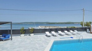 A pool area with a clear view of the sea, lounge chairs, and a covered seating area. - Apartment Franka by Interhome (Pašman/Pašman)