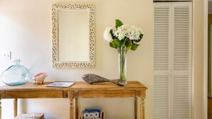 Un bureau en bois orné d’un vase de fleurs blanches, d’un miroir décoratif et d’un petit panier.