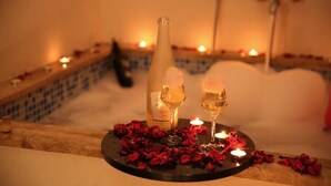 Una bañera con pétalos de rosa y velas, evocando un ambiente romántico.