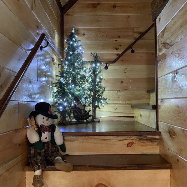 Uma escadaria de madeira decorada com um boneco de neve e um pinheiro de Natal com luzes.