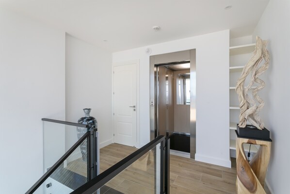A modern interior with a staircase, a white door, and a wooden sculpture.