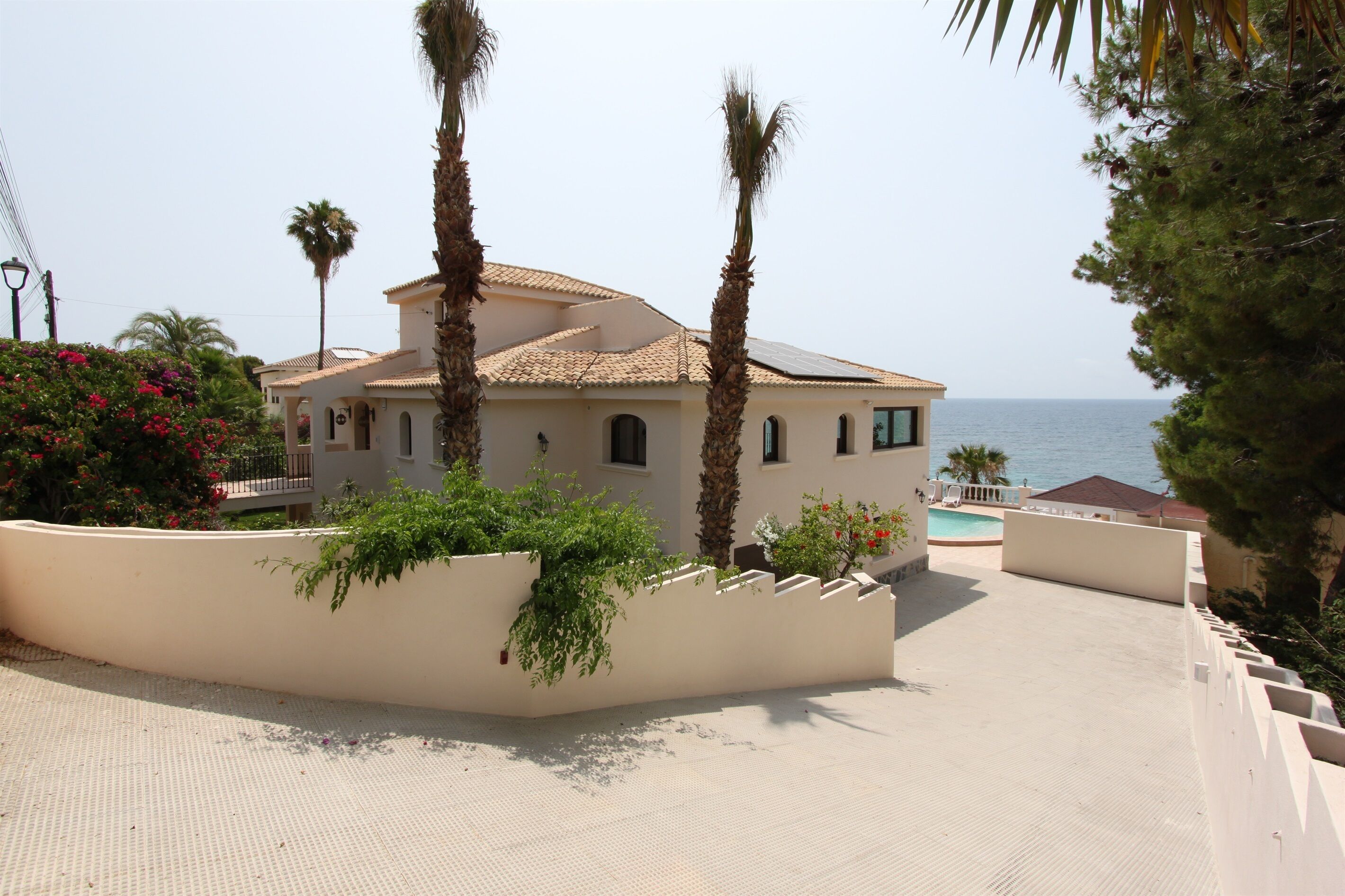 Een villa in mediterrane stijl met een betegeld dak, een zwembad en uitzicht op zee.