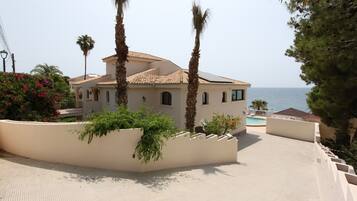 Een villa in mediterrane stijl met een betegeld dak, een zwembad en uitzicht op zee.