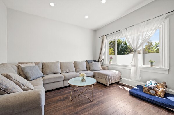 Relax in this inviting living room with a beige sofa, round coffee table, and blue daybed.