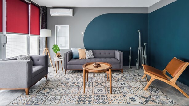 Ein modernes Wohnzimmer mit einem grauen Sofa, einem runden Couchtisch und einem Fenster mit rotem Rahmen.