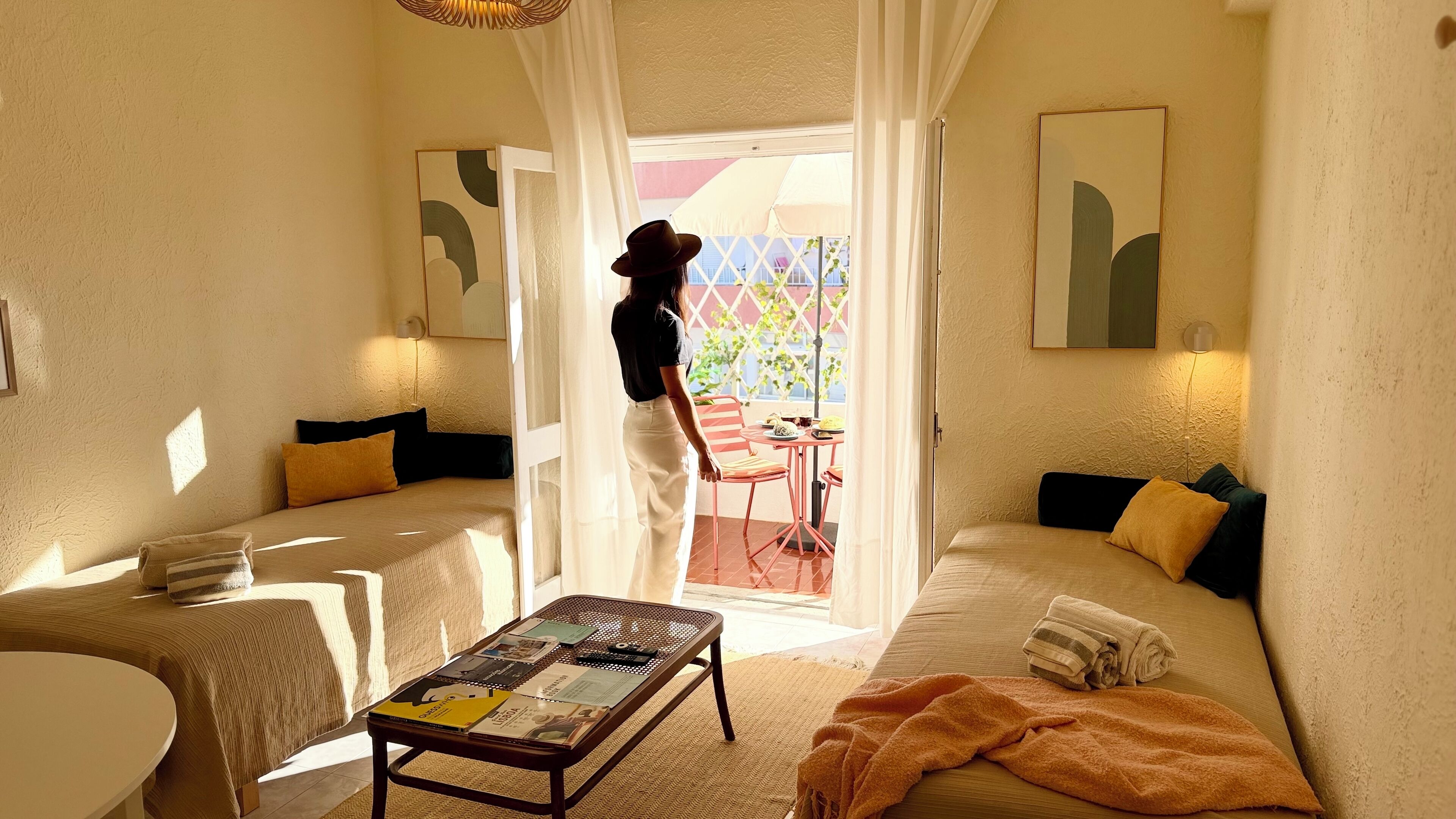 Une pièce confortable avec un canapé, une petite table sur laquelle sont posés des magazines, et une vue sur l’extérieur par une fenêtre.
