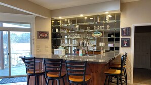 Uma cozinha com espaço de bar, equipada com banquetas, micro-ondas e diversos eletrodomésticos.
