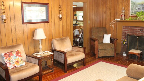 A wooden-paneled living room with a fireplace, a red rug, and multiple armchairs. - Relaxing, quiet country setting. Close to many Mountain activities! (Sugar Grove)