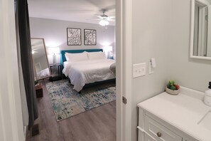 A bedroom with a bed, bedside tables, a ceiling fan, and artwork on the wall.