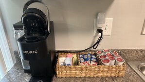 A Keurig coffee maker on a kitchen counter next to a basket of coffee pods and a coffee machine. - Minutes to Keeneland/Airport/UK & more! (Lexington)