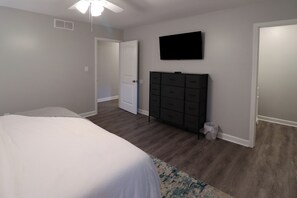 A bedroom with a bed, a dresser, a television, and a door. - Minutes to Keeneland/Airport/UK & more! (Lexington)