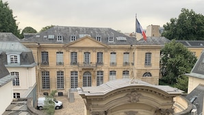 A historic building with a prominent entrance, a flag, and a balcony with wrought iron railings. - Très bel Appartement Familial Parisien aux Pieds des Invalides (Paris)