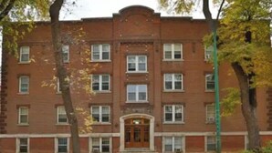 Un edificio de ladrillo de varios pisos con una entrada central y múltiples ventanas.